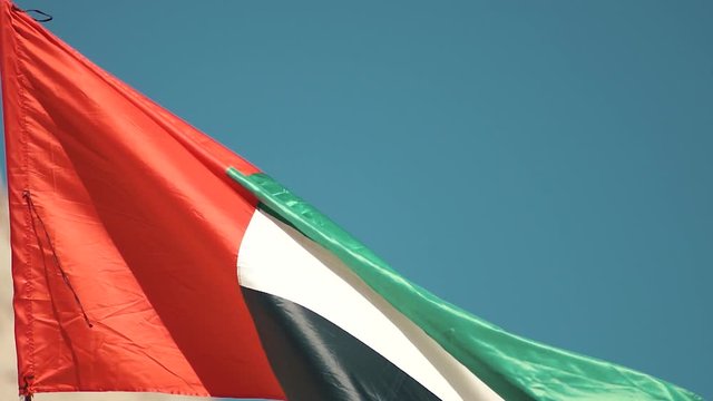 Flag of United Arab Emirates against blue sky in a summer day UAE flag waving in Dubai city , national symbol of UAE. blue sky, uae flag perfect for film, news, digital composition, uae flag day 