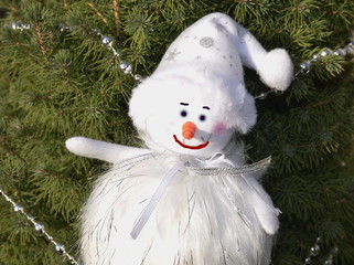 Christmas. Against the background of green fresh spruce branches, a cute smiling snowman.