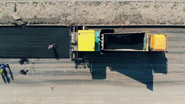 Workers are spreading asphalt on the road. Construction workers working on a road construction.