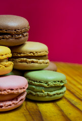 Colored macarons isolated on wooden dish, typical French dish