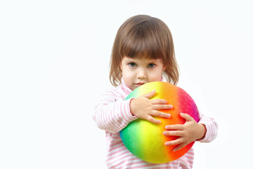 Fototapeta na wymiar Sweet two year old little baby girl with big grey eyes hugs a large ball painted LGBT rainbow ribbon. Adoption and parenting by homosexual couple and families concept. Children against homophobia.