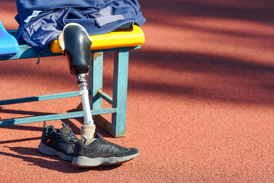 Sneakers and taken off prosthetic legs near the seat at a stadium.