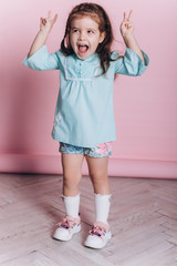 Close up portrait of young cute adorable caucasian kid on soft pink background indoors in studio. Positive concept, childhood happiness concept.
