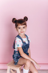 Close up portrait of young cute adorable caucasian kid on soft pink background indoors in studio. Positive concept, childhood happiness concept.