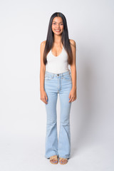 Obraz premium Full body shot of happy young beautiful Asian woman smiling