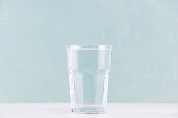 Glass of pure water on the table, blue background