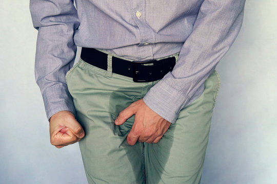 men are scratching penis against blue gray background. People itching crotch. Human body problem or healthcare and medicine concept. incontinence and wet pants