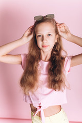 Happy adorable caucasian girl portrait on soft pink background in studio. Childhood, fashion kids, teen girl 