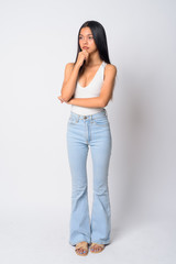 Full body shot of young beautiful Asian woman thinking