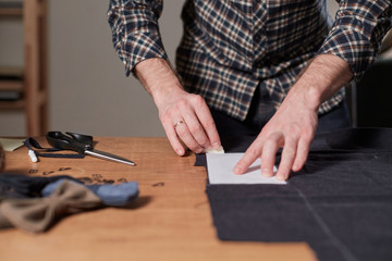 Tailor cutting wool fabric. the line pattern. Craftsman Makes rectangular blanks for Bow ties of woolen fabric. Work with sewing machine in a textile studio.