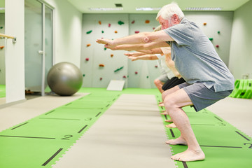 Senior group in fitness class trains leg muscles