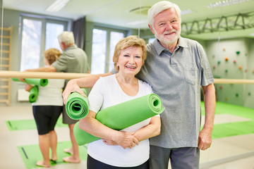 Happy sporty seniors couple with yoga mat