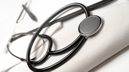 Stethoscope, pen and notepad on white background. Heart treatment concept, cardiology.