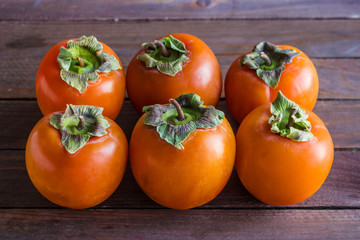 fresh organic persimmons on brown wooden table close up