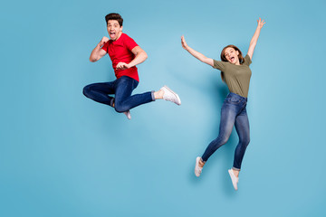Fototapeta na wymiar Full size photo of funky crazy two people spouses students man fight kick hands fists woman jump fool raise arms wear green red t-shirt denim jeans sneakers isolated blue color background