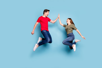 Fototapeta na wymiar Great job. Full length profile side photo of cheerful two romantic people jump give highfive celebrate victory wear modern t-shirt denim jeans sneakers isolated blue color background