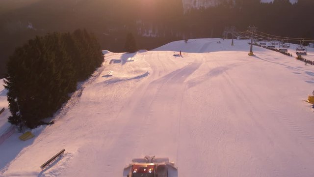 Top Shot Drohne einer Skipiste die fr&uuml;h morgens bei morgenr&ouml;te von pistenbullies aufbereitet wird,