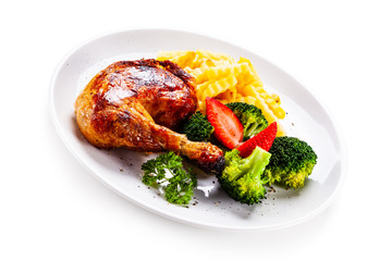 Grilled chicken leg with chips and vegetables on white background