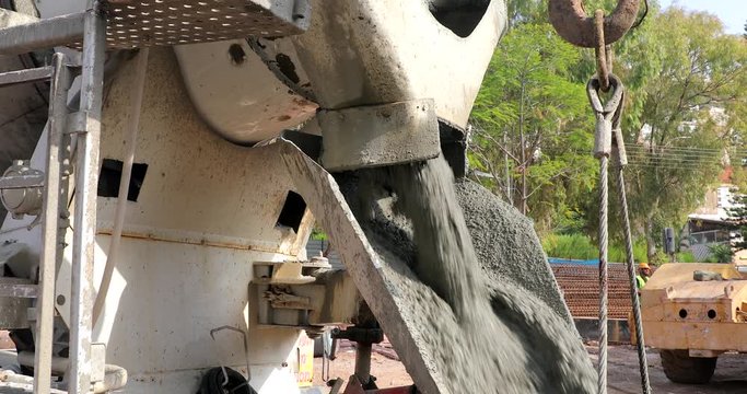 Concrete mixer lorry pouring wet concrete into concrete bucket at the construction site. Cement Mixer Truck pouring cement into crane bucket.
