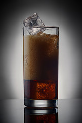 glass of foaming cola with ice