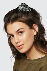 Closeup half-turn face portrait of girl with dark wavy hair, wearing khaki t-shirt. Her hair is...