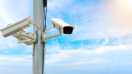 Outdoor security CCTV on the pole with sunlight and blue sky background.