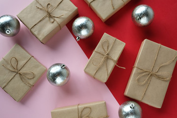 Christmas presents lie on a red-pink background next to silver Christmas balls.