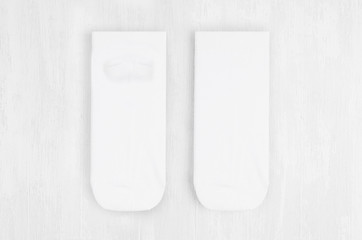 Pair blank white small, low socks flat lay on white wood board, front view, backside - mock up for design, print, presentation, advertising, top view.