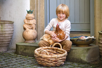 Village life. A country boy with a brown chicken and a big basket in the yard on the steps near the front door.Summer day