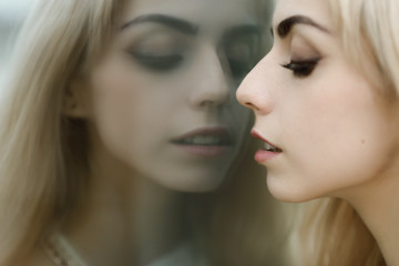 Portrait of a beautiful blonde girl. Reflection in the mirror.