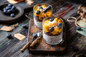 healthy layered dessert white chia seeds pudding, chocolate granola, mango, blueberries