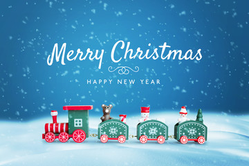 Cute wooden train in snow surrounded by a lot of snowflakes. Merry Christmas text on blue...