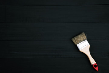 paint brush lying on wooden clean table. Dark black background. Top view. Leave Copy space to write a message.