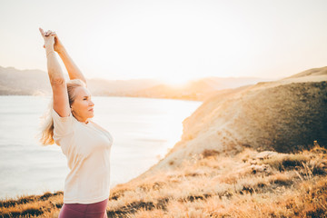 Woman practicing Yoga, meditation close to the sea. She doing different poses on beautiful...