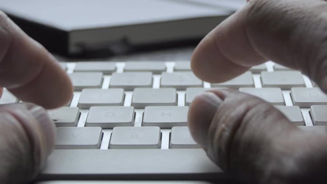 typing on a white keyboard from the writer's point of view with black notebook