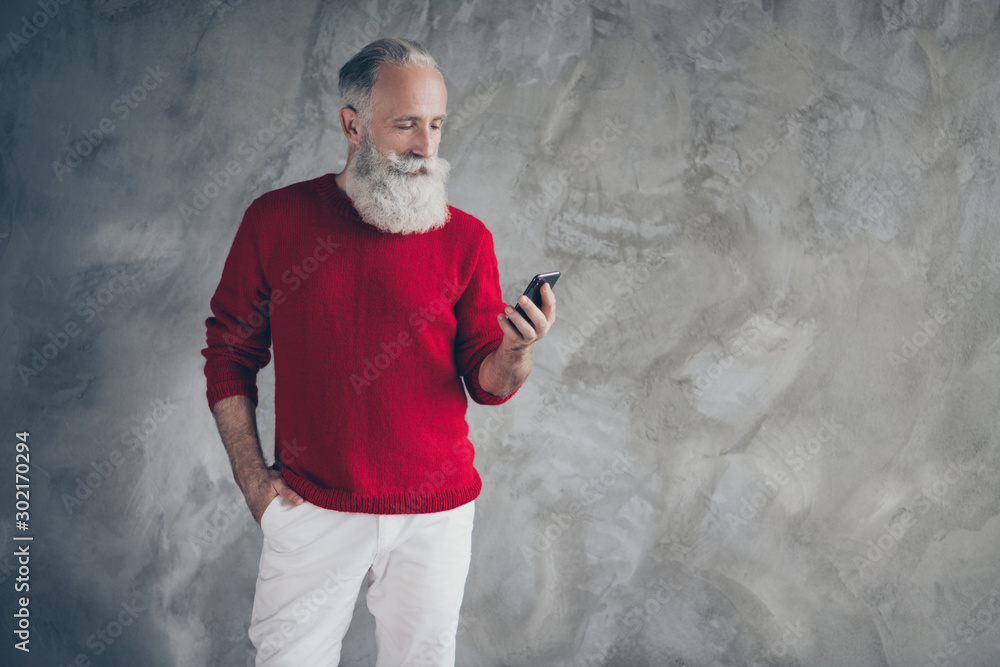 Poster Serious masculine modern old man stand copyspace use smartphone search x-mas season discounts type newyear congratulations wear red sweater white trousers isolated grey color background