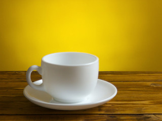 White coffee cup and plate is staying on wooden table