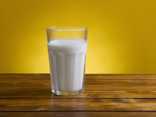 Glass with fresh milk on wooden table