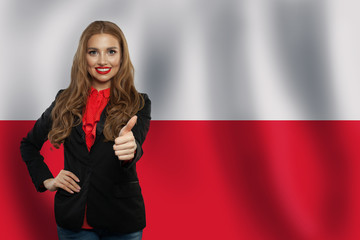 Cute young woman showing thumb up on the Poland flag background.