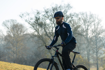 Obraz premium Cyclist in pants and fleece jacket on a modern carbon hardtail bike with an air suspension fork rides off-road.