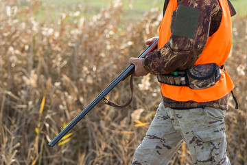 Hunting period, autumn season open. A hunter with a gun in his hands in hunting clothes in the...