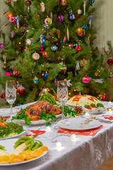 Festive Christmas served table against beautiful green pine tree decorated with many colorful new year toys. Xmas dinner, delicious food, christmas turkey. Winter holidays celebration at cozy home