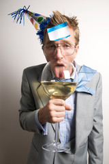 Drunken businessman wearing a party hat licking an oversized wine glass with a name tag stuck to his forehead 
