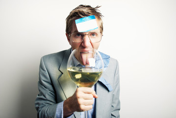 Drunk office worker with a name tag stuck to his forehead licking an oversized wine glass 