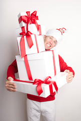 Smiling man carrying stack of Christmas presents matching his red and white outfit