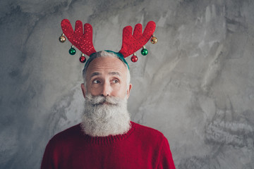 Portrait of stylish funky old man in reindeer headband enjoy christmas party x-mas celebration wear red modern sweater isolated over grey concrete wall color background