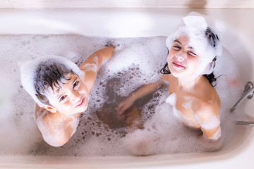 Two kids taking a bath looking a camera
