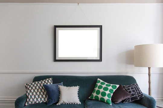 Empty picture frame hanging above a blue sofa in a living room