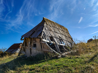 Fototapeta premium Small ruined wooden house built in traditional style found in distant isolated mountain village while trekking in the nature