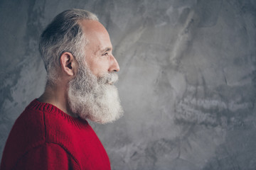 Profile photo of positive aged guy looking empty space deeply thinking cheerful wear red knitted pullover hipster santa outfit isolated grey color concrete wall background